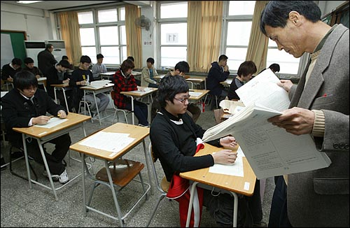 2005학년도 대학수학능력시험이 치러지는 11월17일 오전 서울 여의도고등학교에서 감독관이 시험지를 배포하고 있다. 